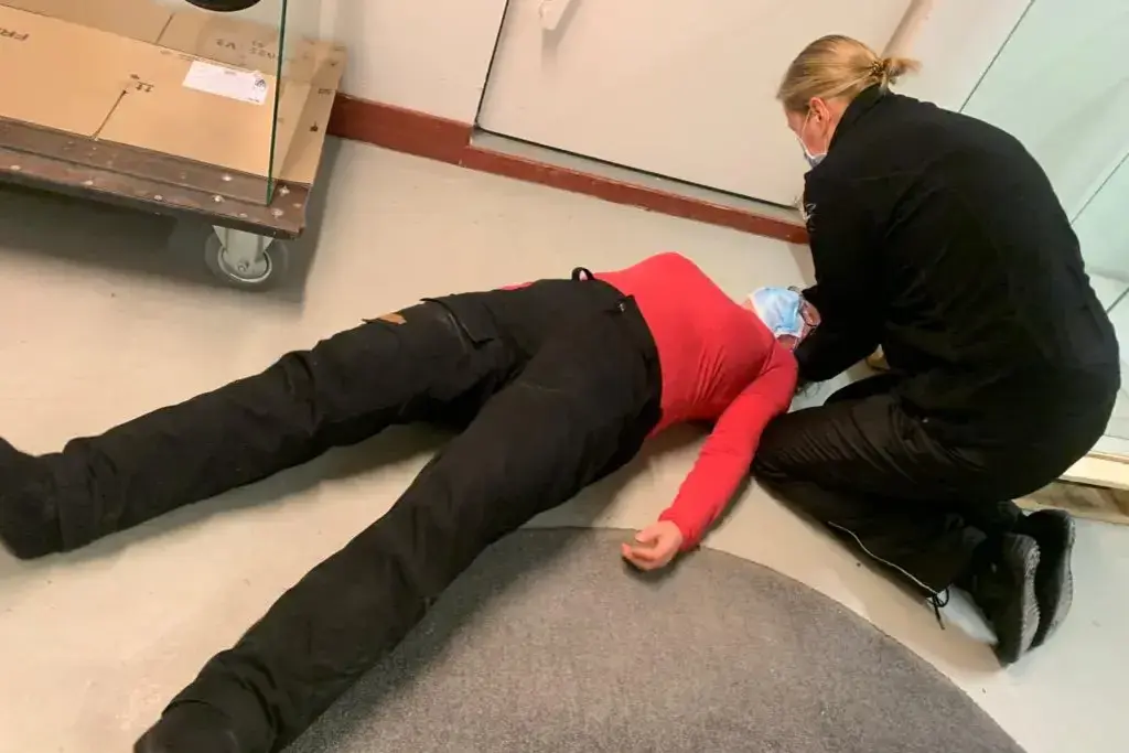 Ensihoitaja tarkistaa maassa makaavan henkilön niskatuen.