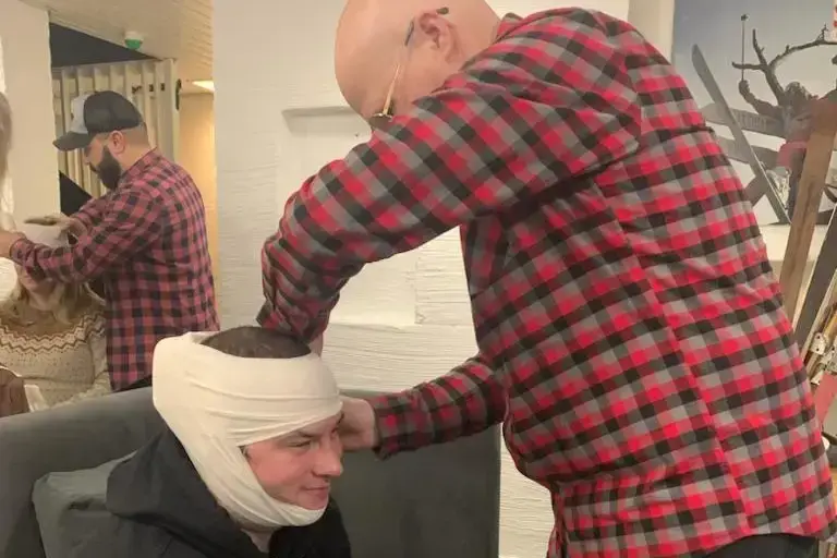 Henkilö sitoo toisen pään ympärille siteen ensiapuharjoituksessa.